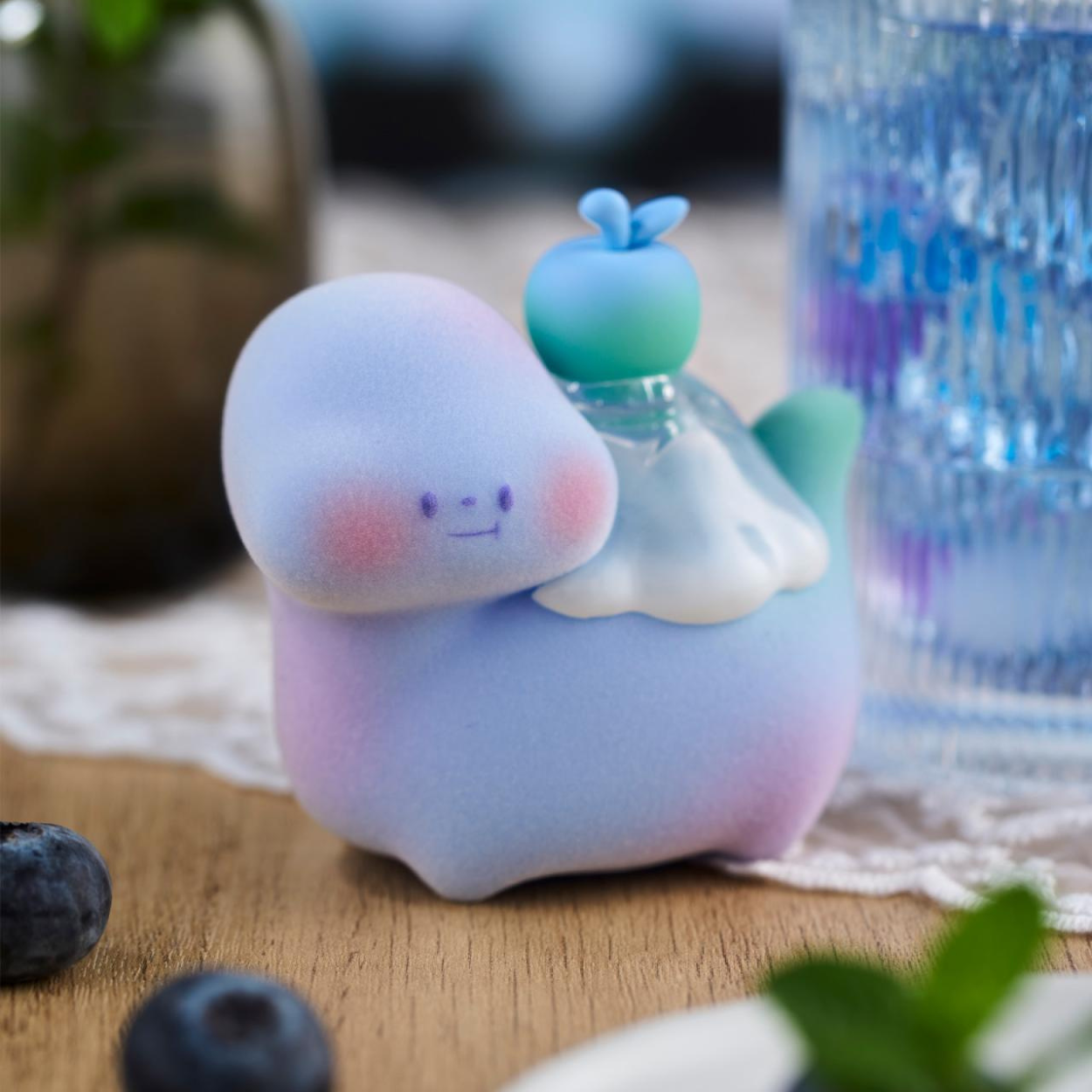 Cute plush toy resembling a cloud with a small blue character on top, sitting on a wooden surface with blurred background.