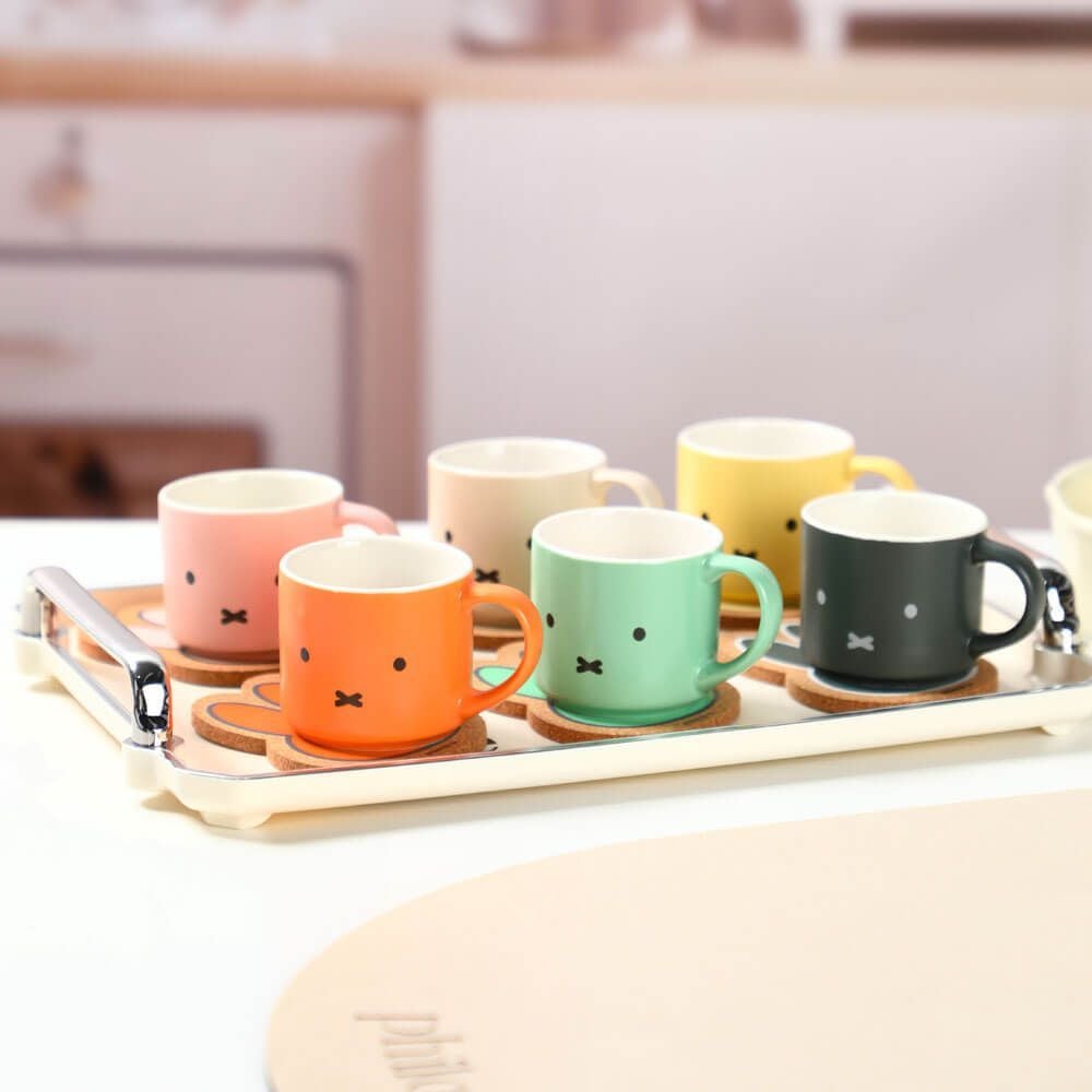 Set of colorful mugs with facial expressions on a tray in a kitchen setting