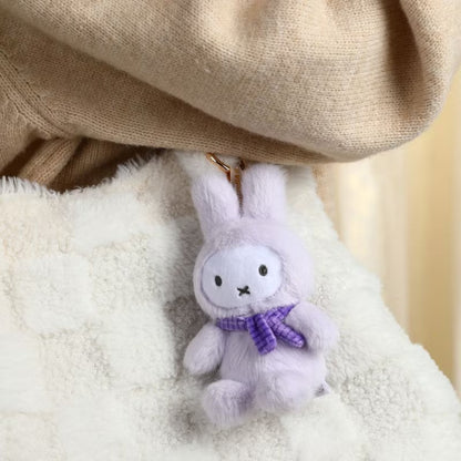 Plush bunny toy with a purple bow tie on a soft surface