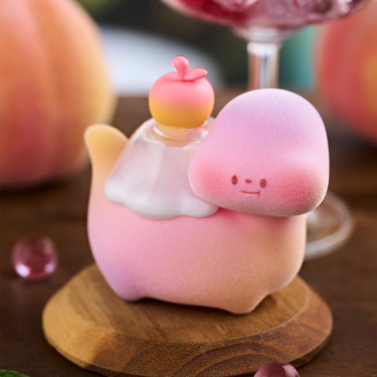 Cute pink plush toy with a small character on top, sitting on a wooden stand.
